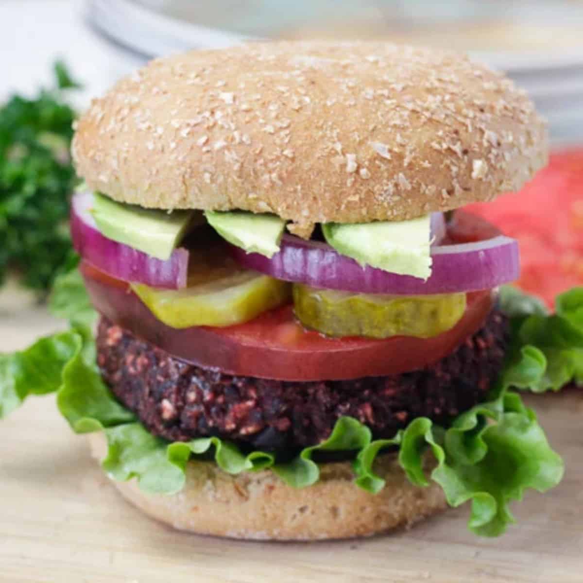 vegan burger with tomatoe, onion, pickle and avocado.