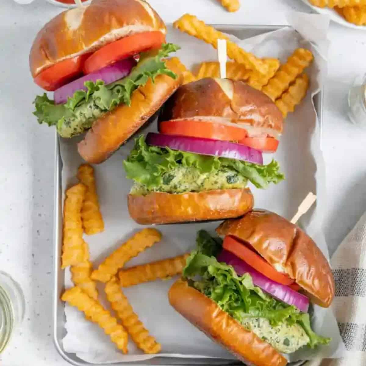 three haphazzardly placed tofu burgers on a baking tray with fries.