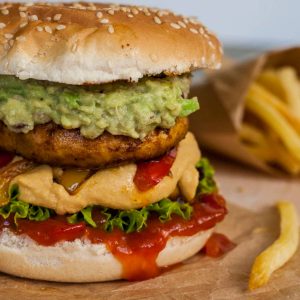 a mushroom burger topped with guacamole and cheese sauce.