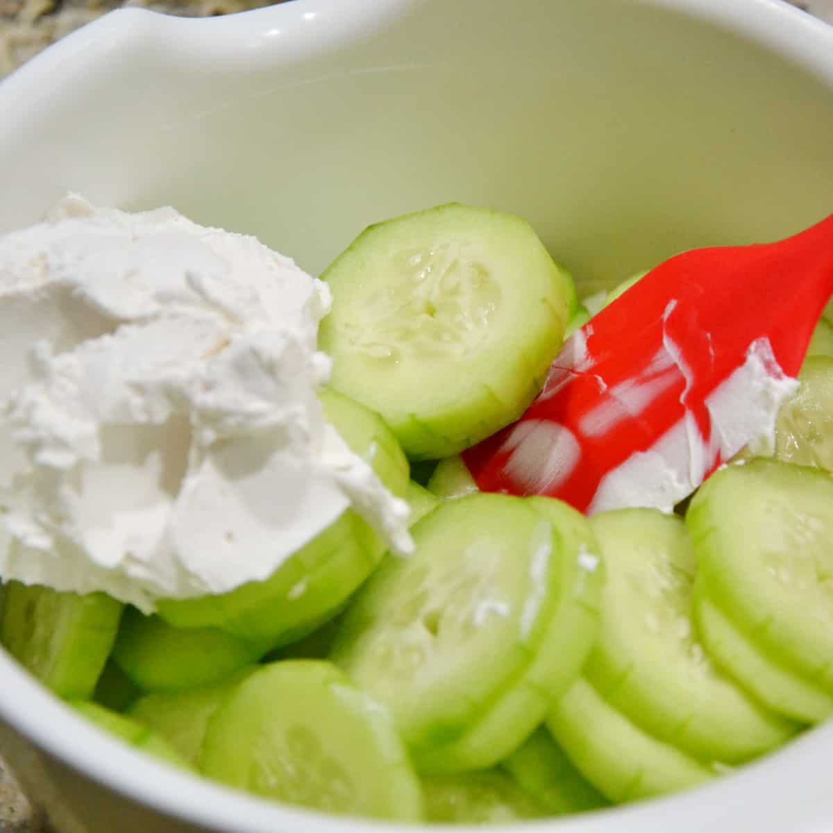mixing cucumbers with sour cream step three.