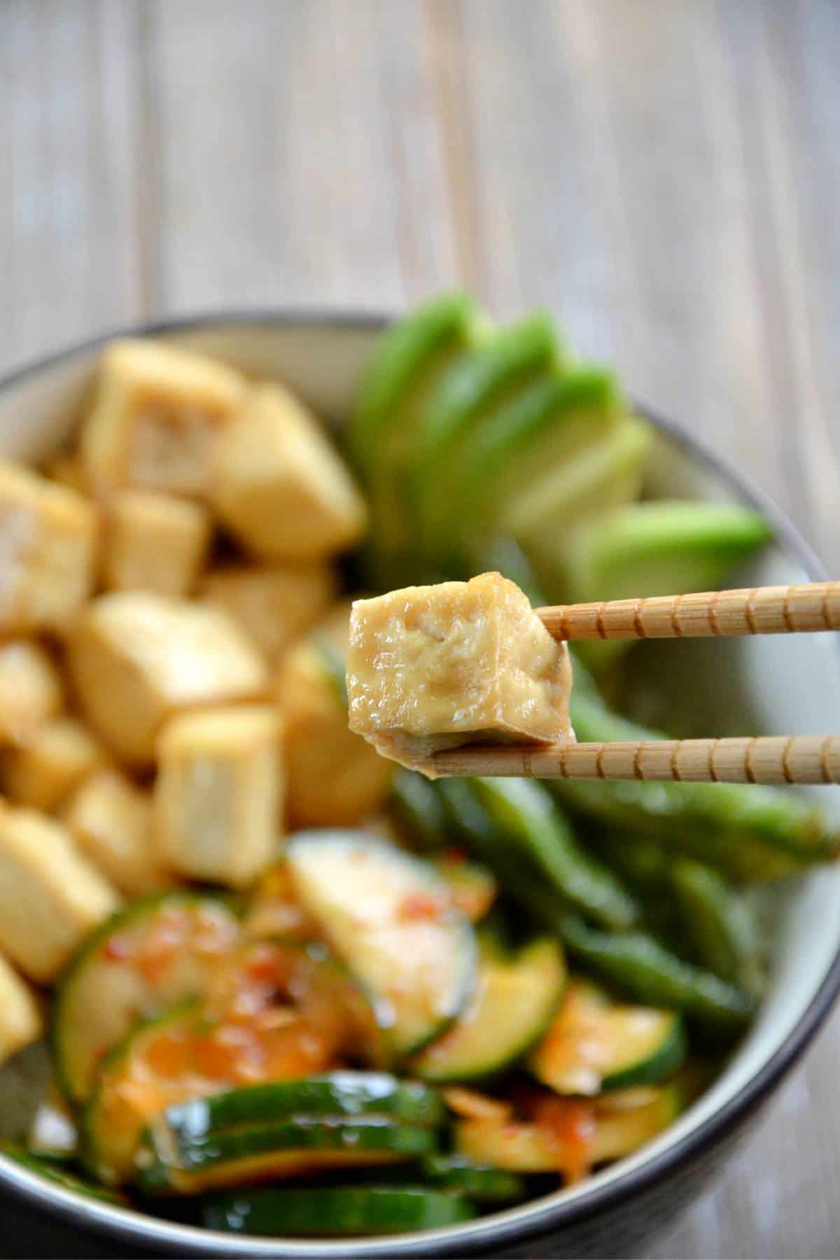 texture of air fried tofu held by wooden chopsticks.