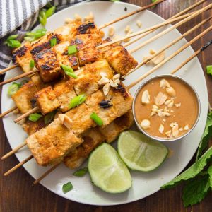 peanut tofu skewers with peanut dipping sauce and limes.