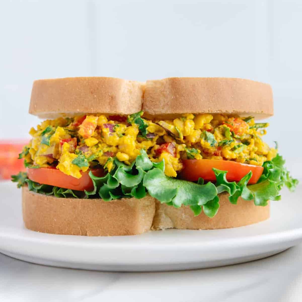 beautiful and bright yellow curried chickpeas salad between two bread slices.