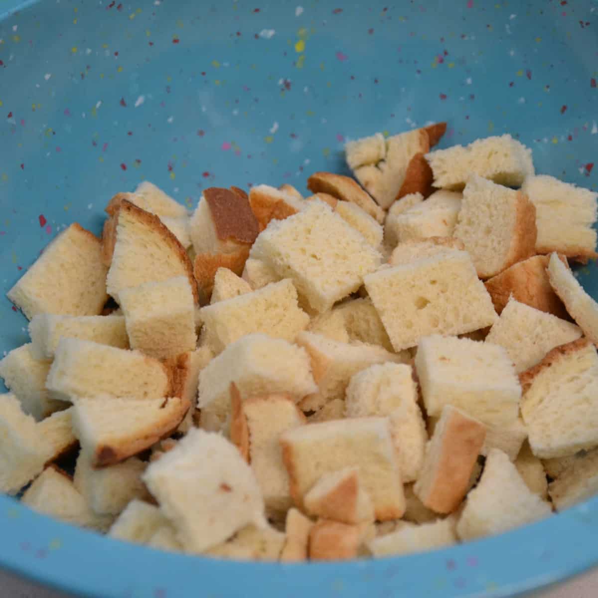 step two in making croutons with bread pieces in bowl.