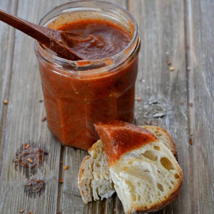 jar of marinara with wooden spoon inside and bread dipped in marinara.