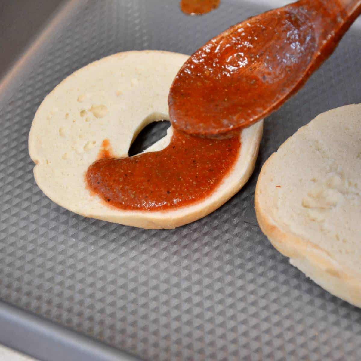 step two assembling pizza bagels with sauce.