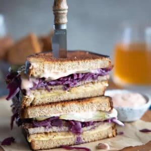stacked sandwich with a knife through the top.