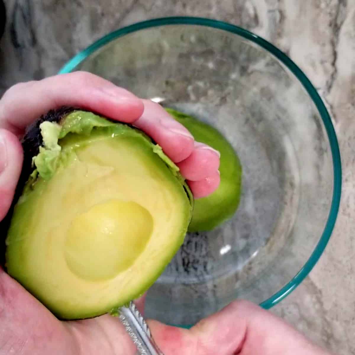 scooping avocadoes into a bowl.
