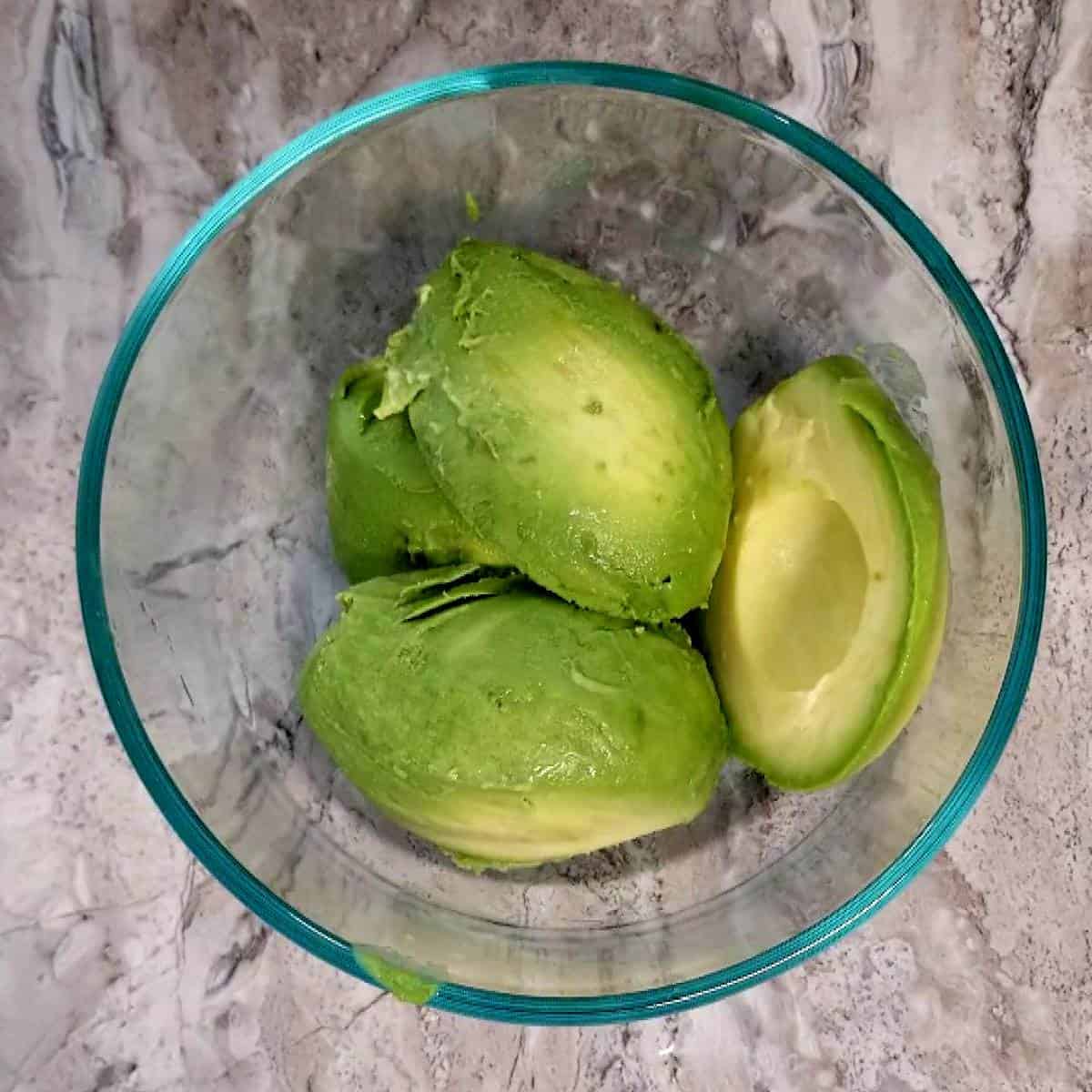 four halves of avocado laying in bowl.