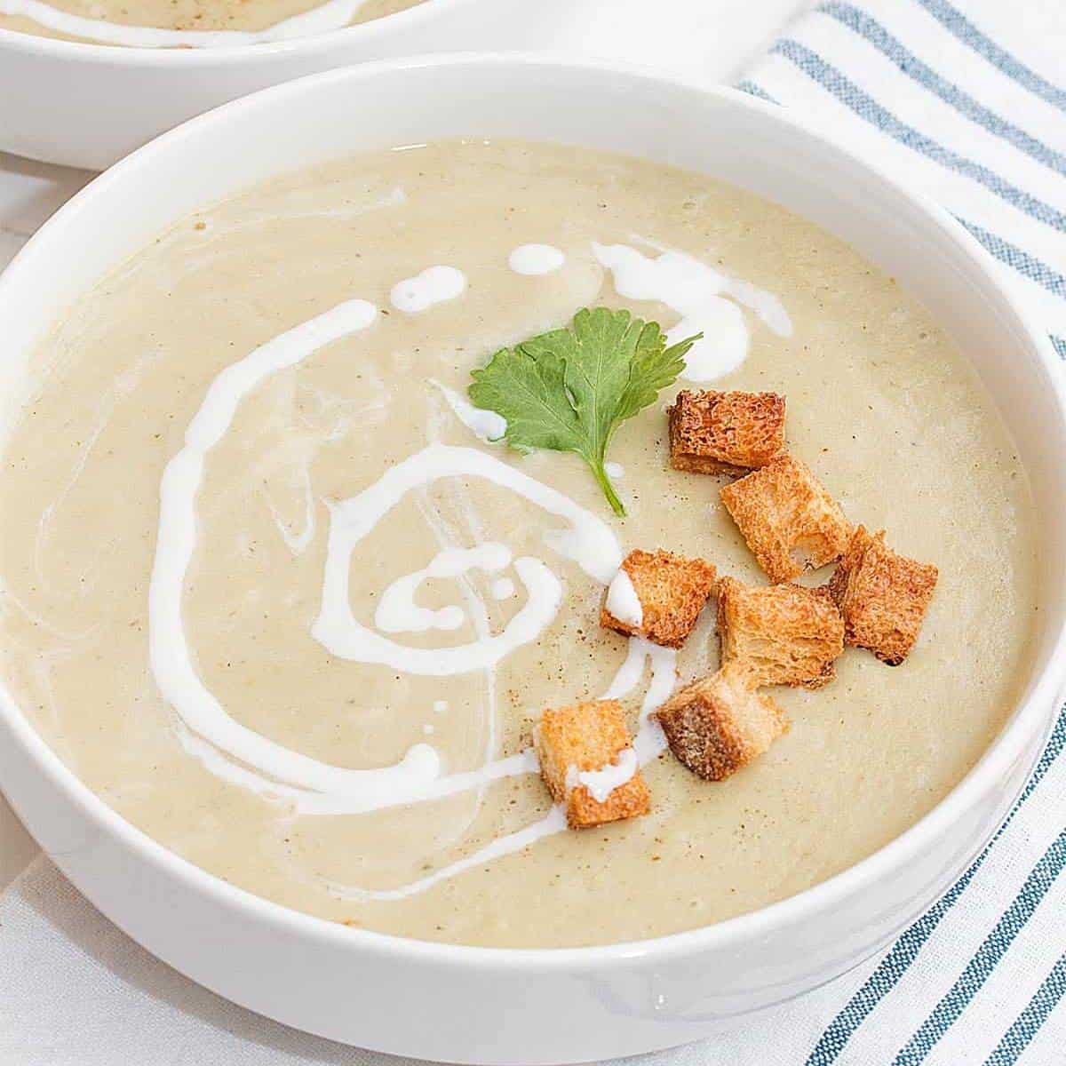 cream colored soup swirled with cream topped with croutons.
