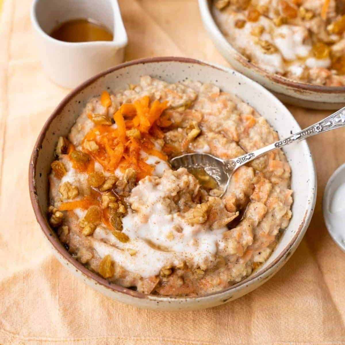 bowl of oatmeal with carrots and toppings swirled in.