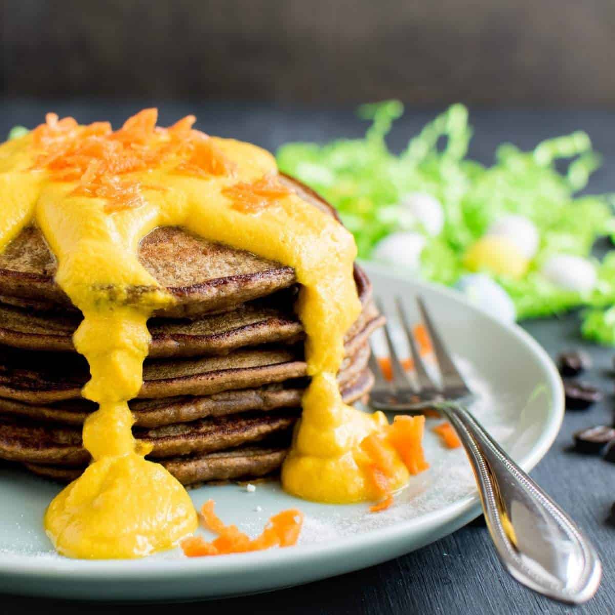 a stack of pancakes with orange frosting running down sides and a fork beside.