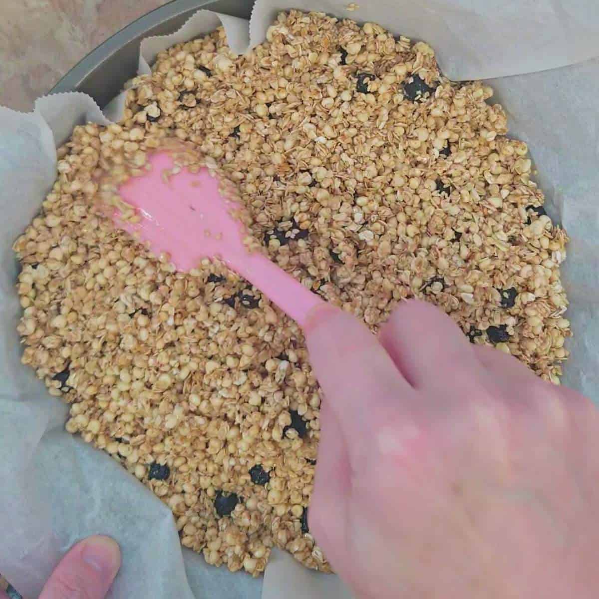 step six putting granola in a baking pan with parchment paper.