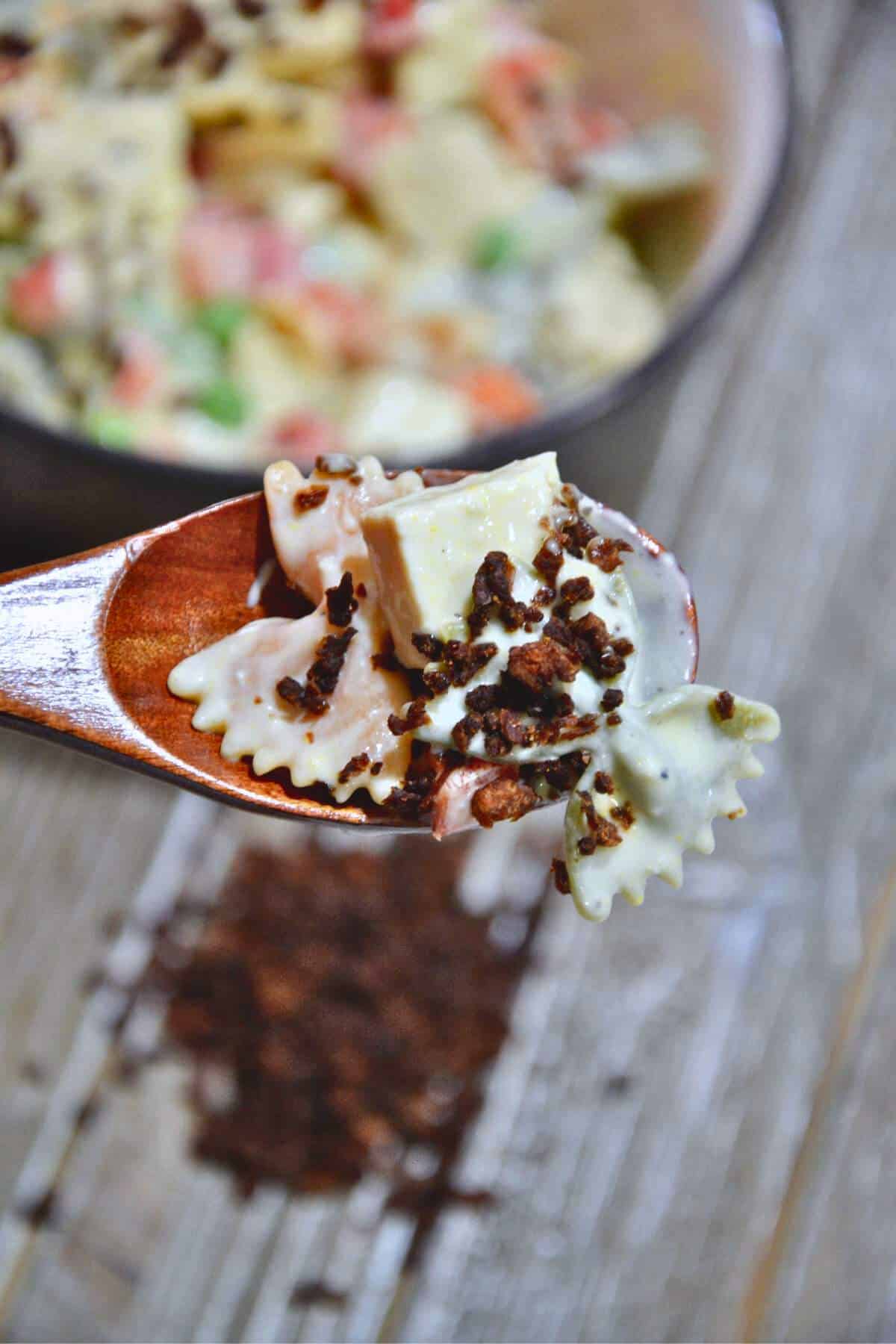 vegan bacon bits topping a salad in a wooden spoon.