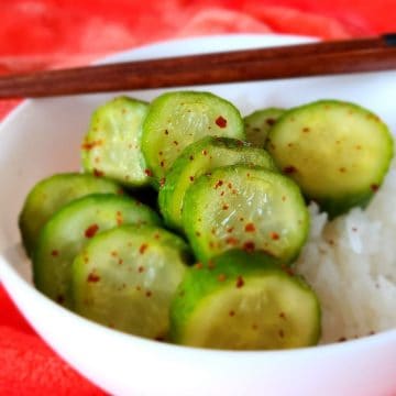 small cucumber coins in bowl with rice and chopsticks.