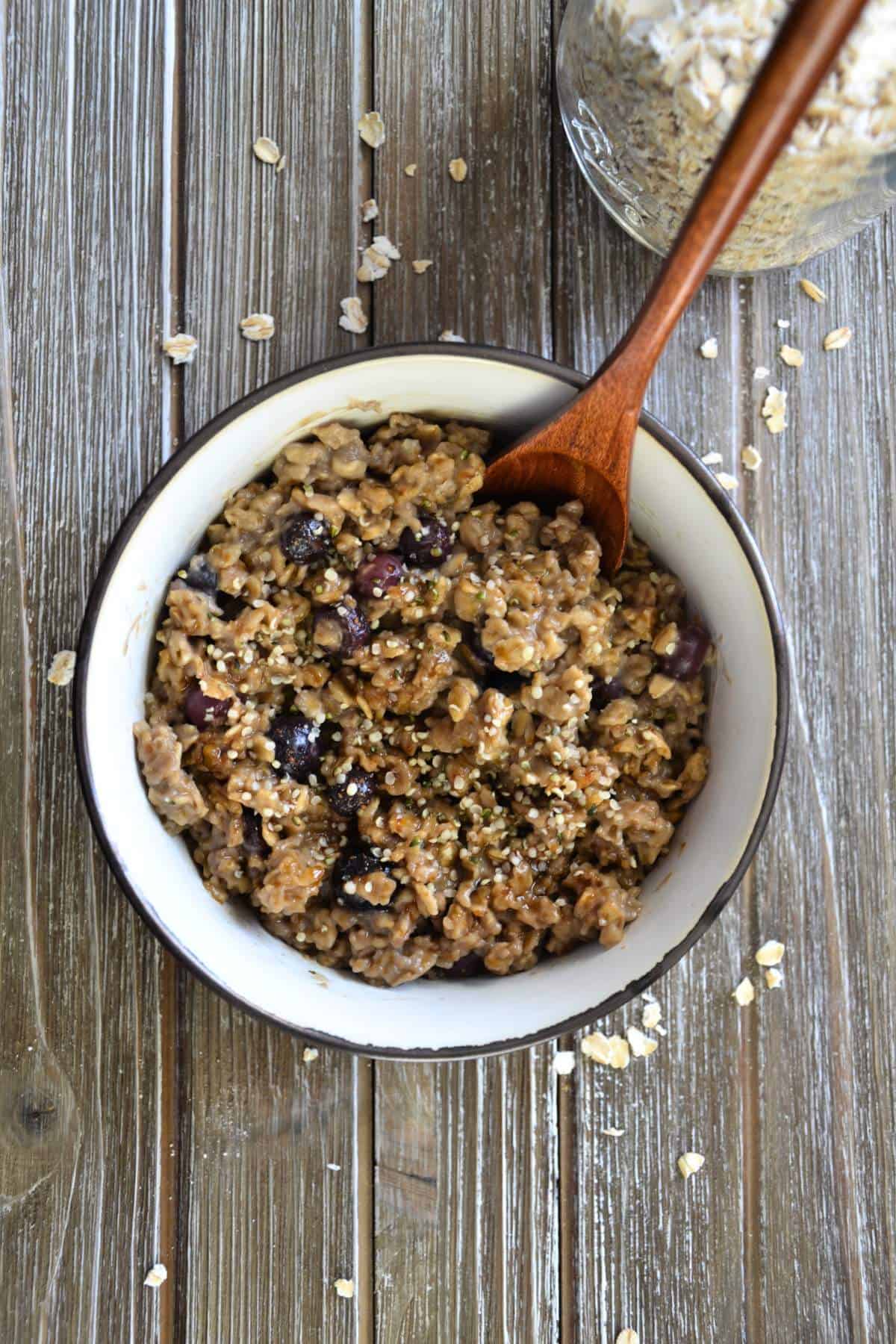 bowl of blueberry oatmeal with oats in background.